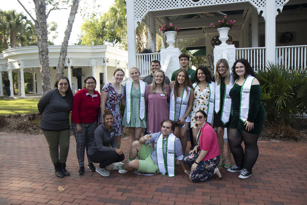 A group of students and employees, adorned with Stetson University sashes, gather for photo.